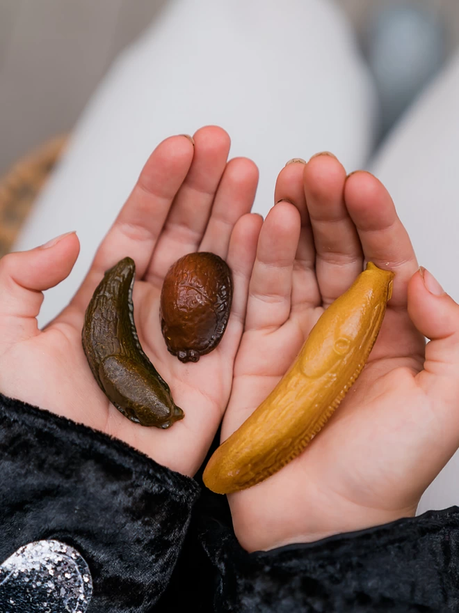 Solid chocolate slugs in various slimy poses held in child's hands
