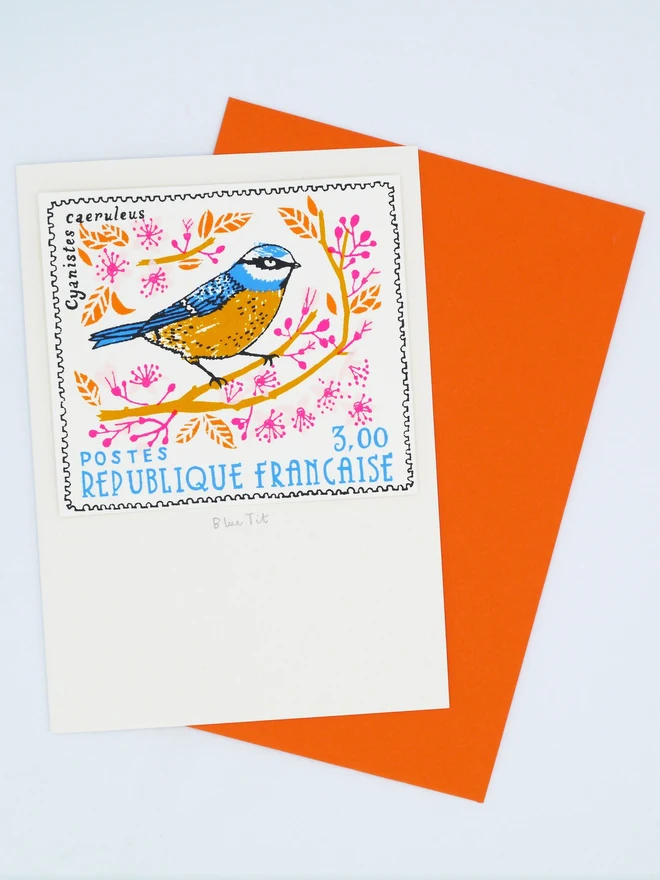Bird Stamp Card Blue Tit/ French Stamp Card, a white card with a colourful bird design in the centre against an orange envelope on a white background. 
