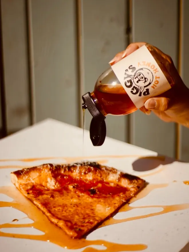 Hot Honey being drizzled on a pizza