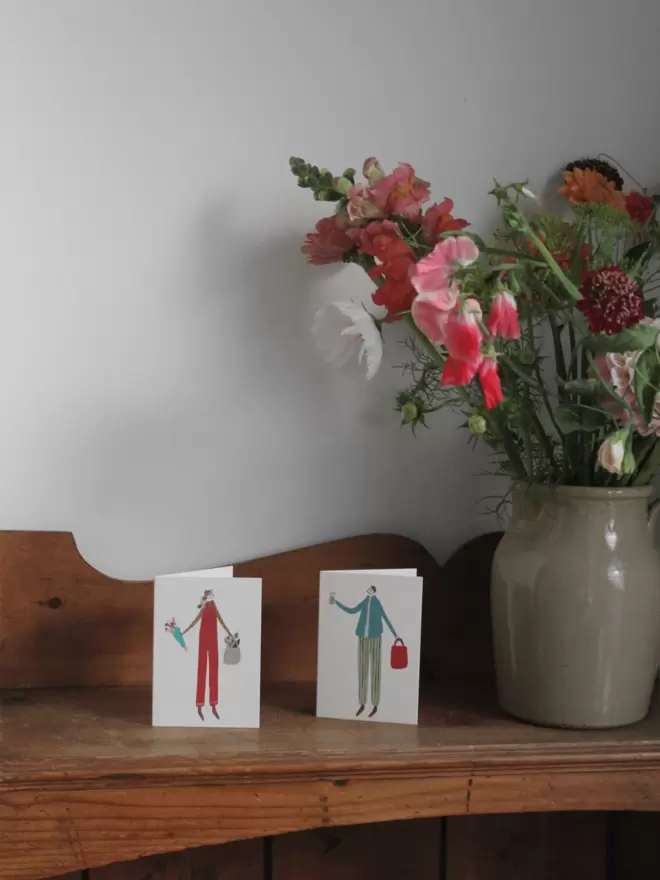 greetings card with a girl and a boy on next to fresh flowers