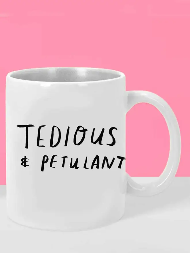 White mug with black writing which says 'tedious & petulant'