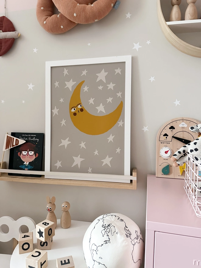 A moon illustration print for a Child's nursery, playroom or kids bedroom. Styled on a shelf around other small business decorations. 