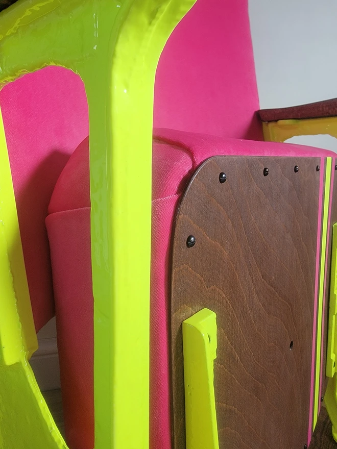 Detail close up of hot pink velvet cinema seat with enone yellow legs