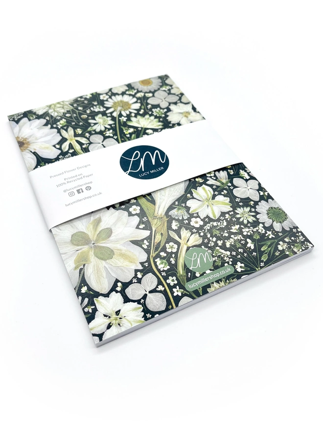 Lined Notebook with cover design created from pressed white flowers on a black background.