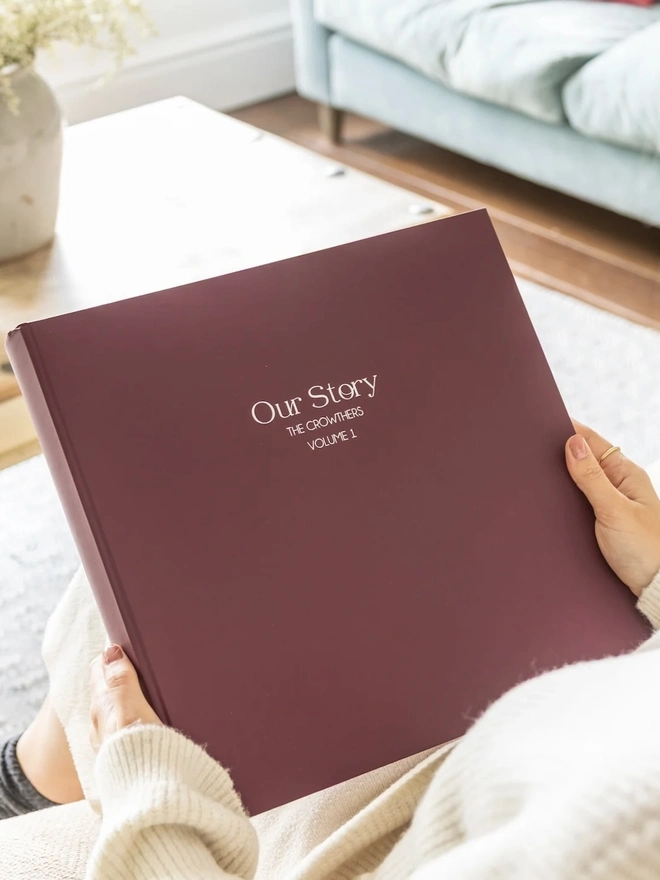 A Luxurious Large Photo Album being held by a woman on a sofa.