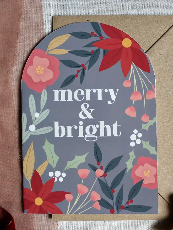 merry and bright floral christmas card. arch shaped card illustrated with flowers and emblazoned with merry christmas.