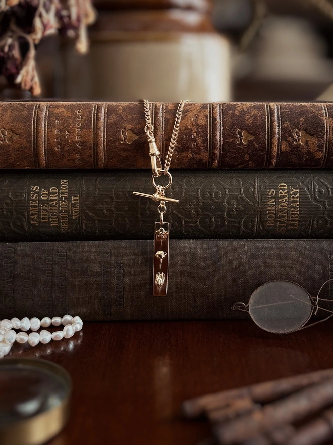 Gold plated sterling silver Motherhood bar pendant watch chain necklace draped over vintage books