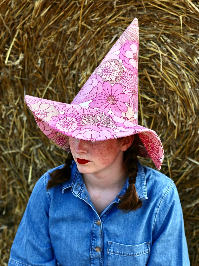 Pink witch hat worn by a young lady, made from sustainable upcycled vintage fabrics