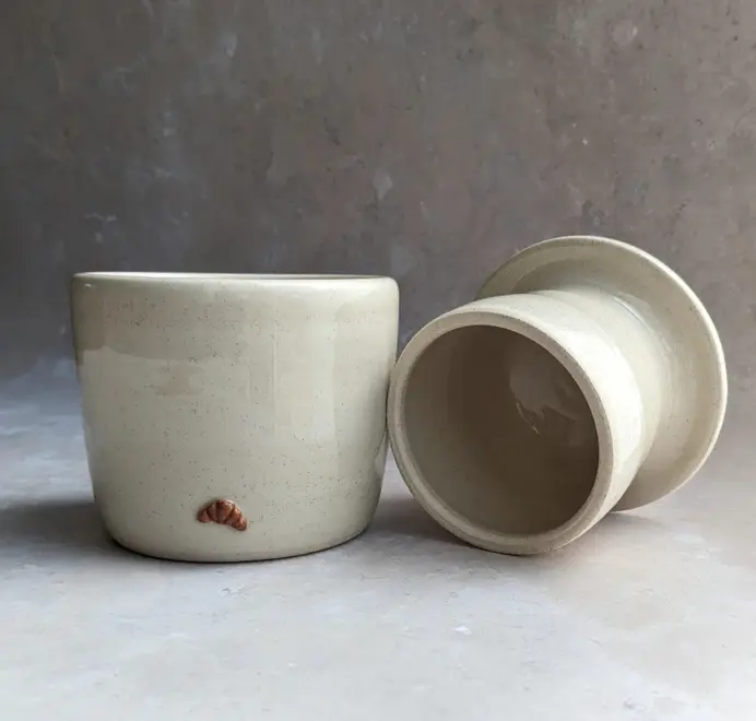 Croissant Butter Crock in vanilla bean glaze with a small croissant design on the front, set against a clean white marble background.