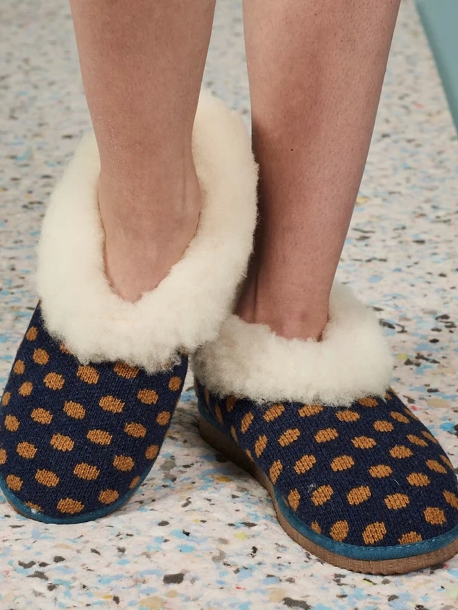 Women's Lambswool & Sheepskin Boot Slippers, a woman wearing a pair of boot slippers on a decorated floor. 
