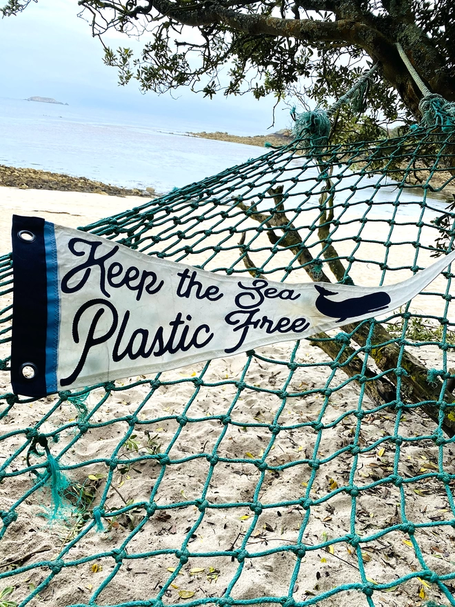 Keep the sea plastic free pennant on a ghost net hammock on a beach