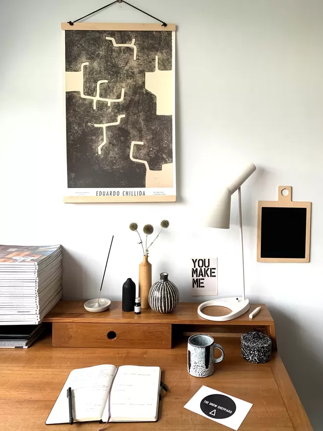 hang over desk with Eduardo Chileada artprint inside. various desk decorations and lamp inshot.