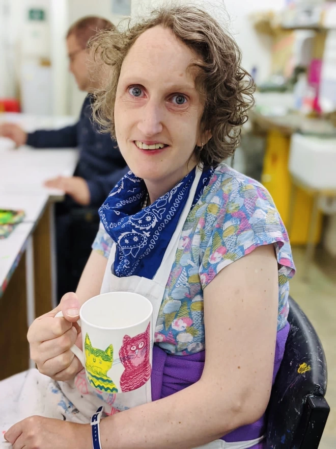 Happy artist holding charity miaow for now fine bone china cat gift mug featuring bright colour cats