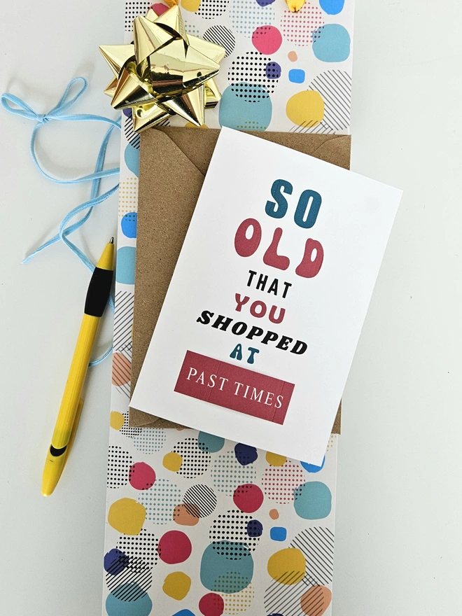 A photograph of the front of a humorous A6 greeting card illustrated using brightly coloured text and the retro shop logo. The text says so old you shopped at Past Times.
