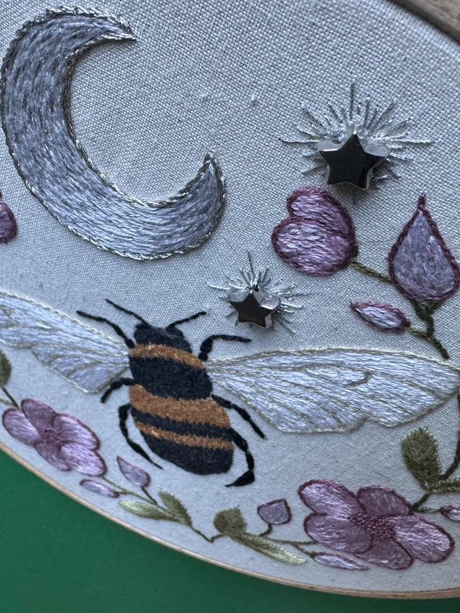 An embroidery hoop bee moon stars flowers