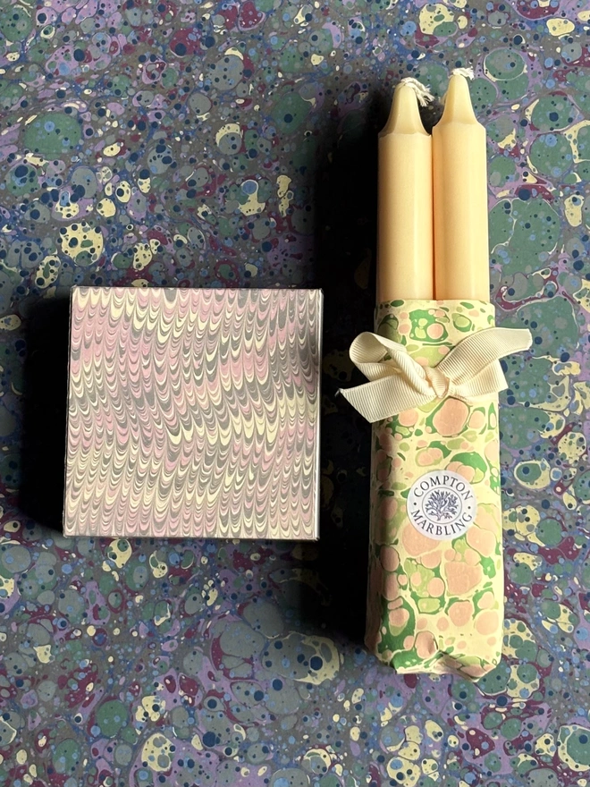 Wrapped candles in hand marbled paper with a square box of matches