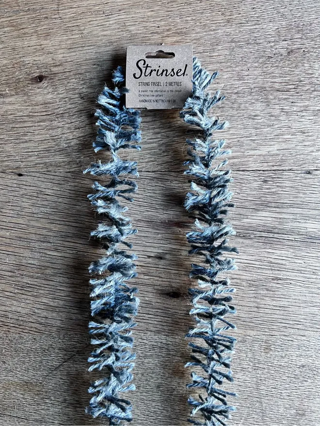 2 metre length of Silvery Pewter Strinsel - string eco tinsel packaged with kraft header label on oak table top