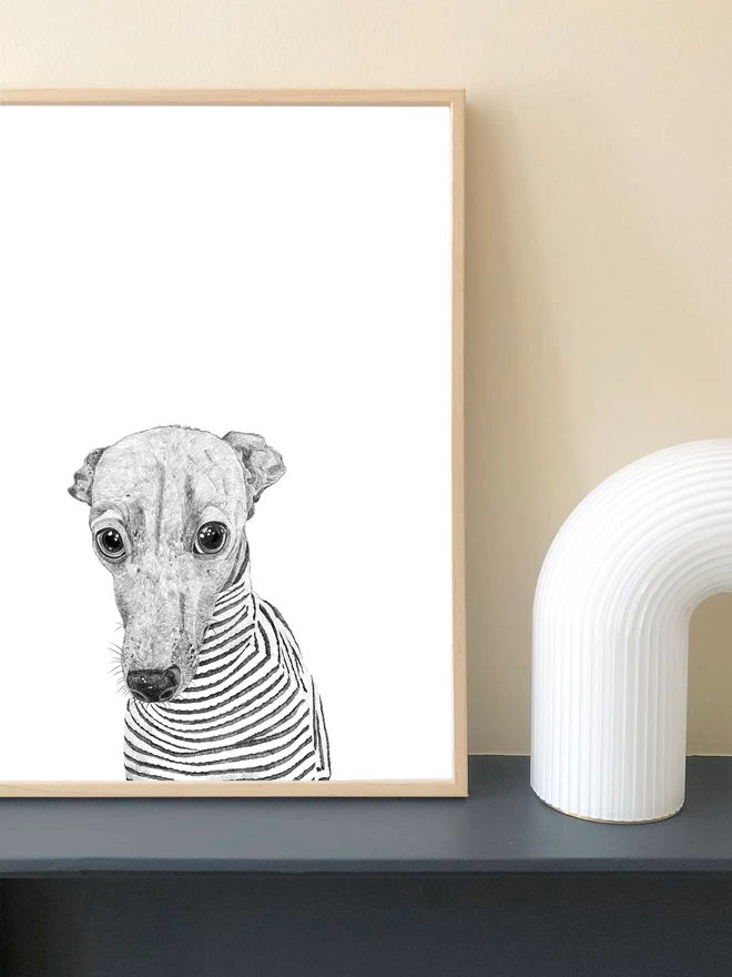 Art print of a hand drawn whippet in a stripey jumper displayed in a frame