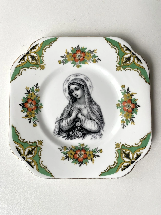 a vintage plate with a really ornate border has the victorian black and white illustration of the virgin mary in the centre