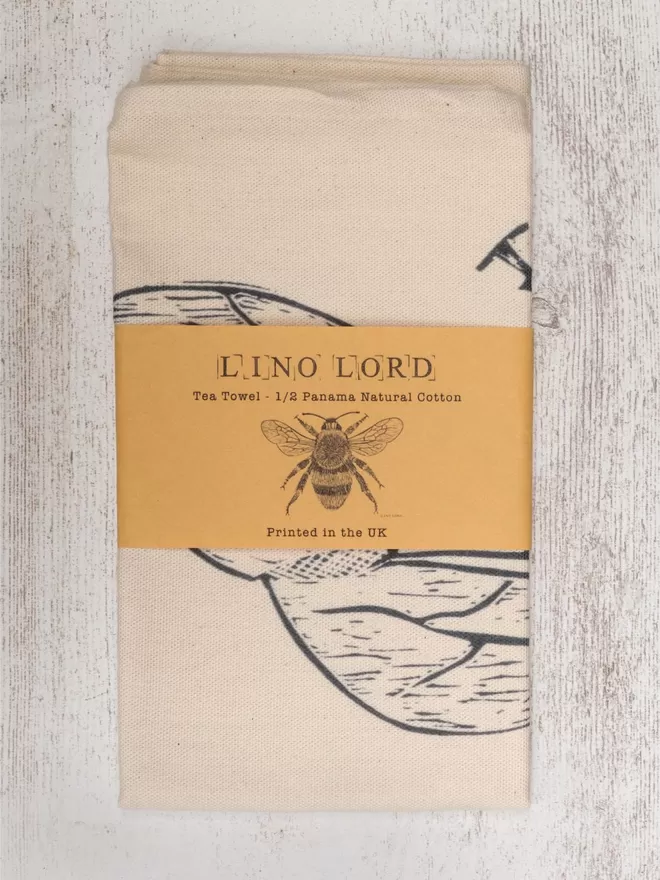 Picture of a tea towel with an image of a bee, taken from an original lino print