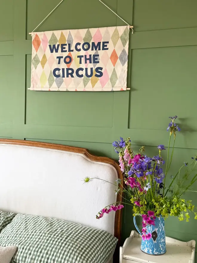 'Welcome To The Circus' Cotton Wall Hanging, hanging on a green wall. 