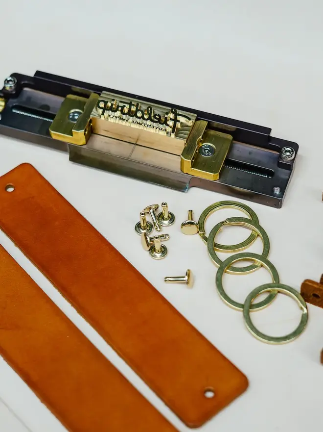 'fieldtrip' handmade leather keyring. tools for embossing a leather keyring photographed laid out on a white surface.