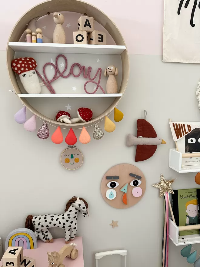 'Play' wall hanging sign for kids playroom sitting up on a shelf. 