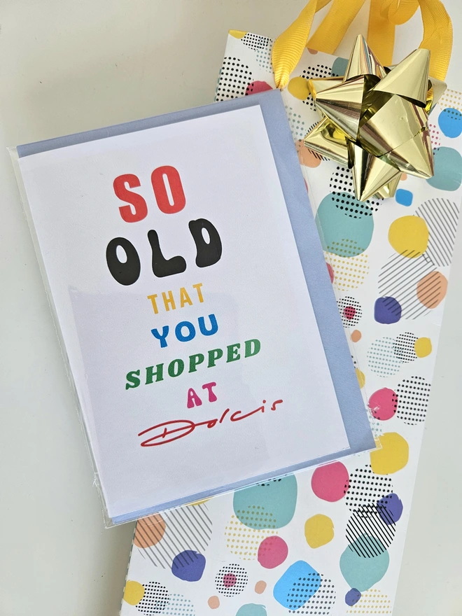 A photograph of the front of a humorous A6 greeting card illustrated using brightly coloured text and the retro shop logo. The text says so old you shopped at Dolcis