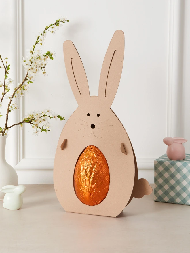 orange milk chocolate easter egg. a chocolate egg in orange foil in a cardboard rabbit