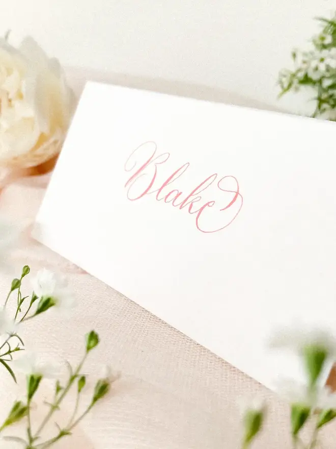 personalised calligraphy place cards. white place card with name in calligraphy pink ink.