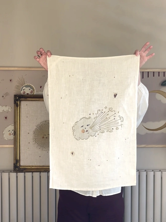'Love Cloud' Linen Tea Towel, a person holding up a tea towel with a cloud motif on it. 