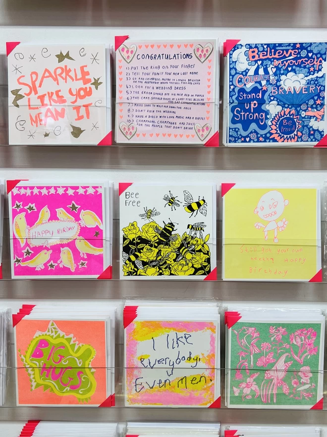 A riso printed card featuring a yellow & black Bee design & the words Bee Free on a rack