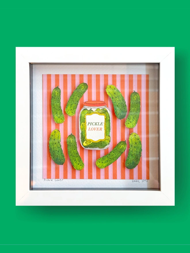 Charming framed collage featuring vibrant illustrated pickles, set against a colorful red and pink striped background, with gherkins and a pickle lover's jar. Perfect for pickle enthusiasts and lovers of quirky food art.