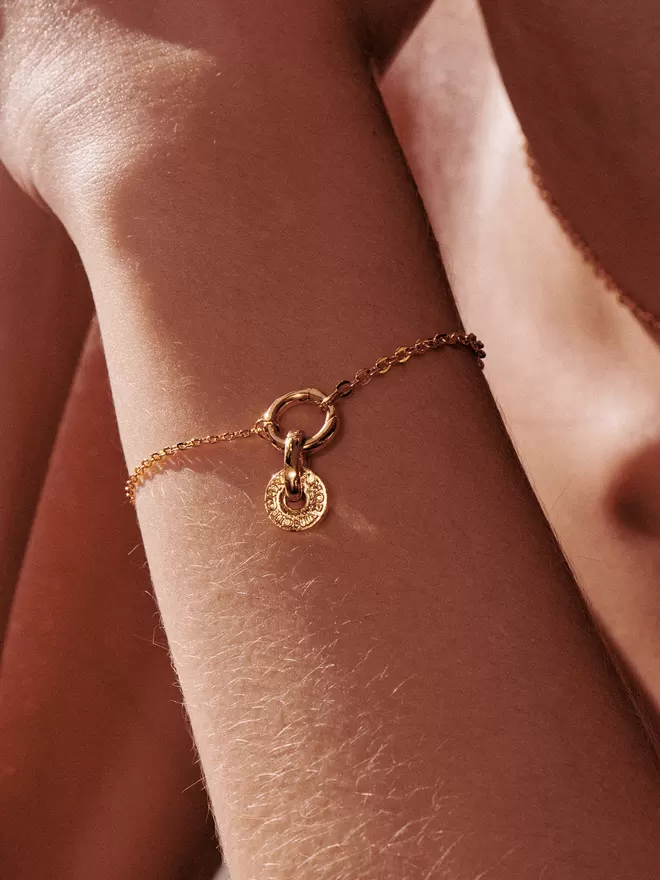 woman wearing gold bracelet with charm