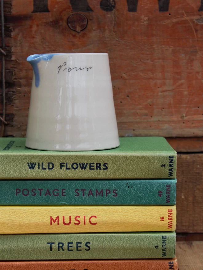 handmade ceramic pouring jug on a stack of vintage books