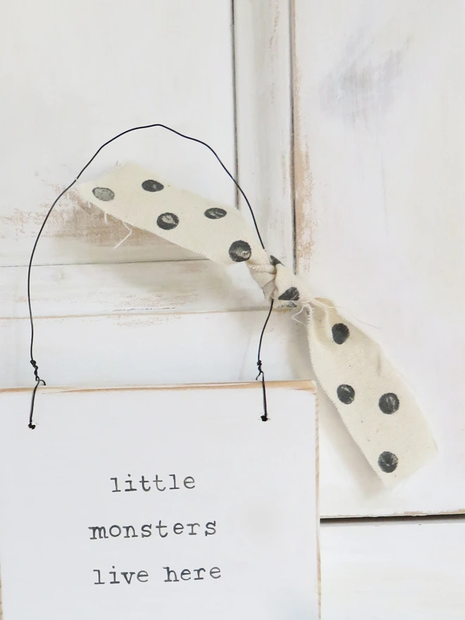 hand painted white wooden sign with hand painted little monsters message