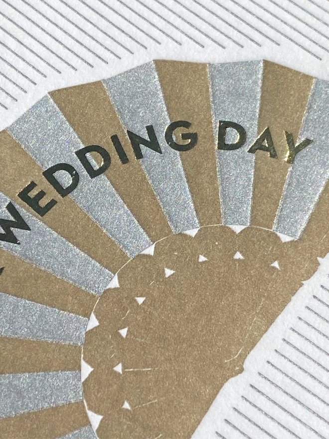 White and silver striped card with silver and gold fan on it with  gold text reading 'Wedding Day'