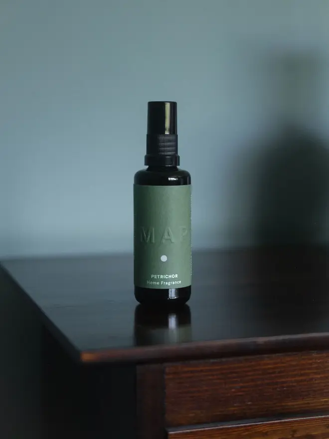 petrichor earthy home fragrance spray. spray bottle photographed on wooden surface. 