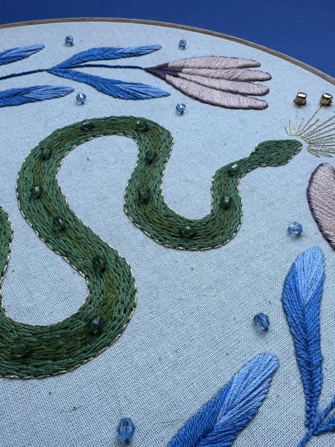 Close up of an embroidered snake with beads and flowers 