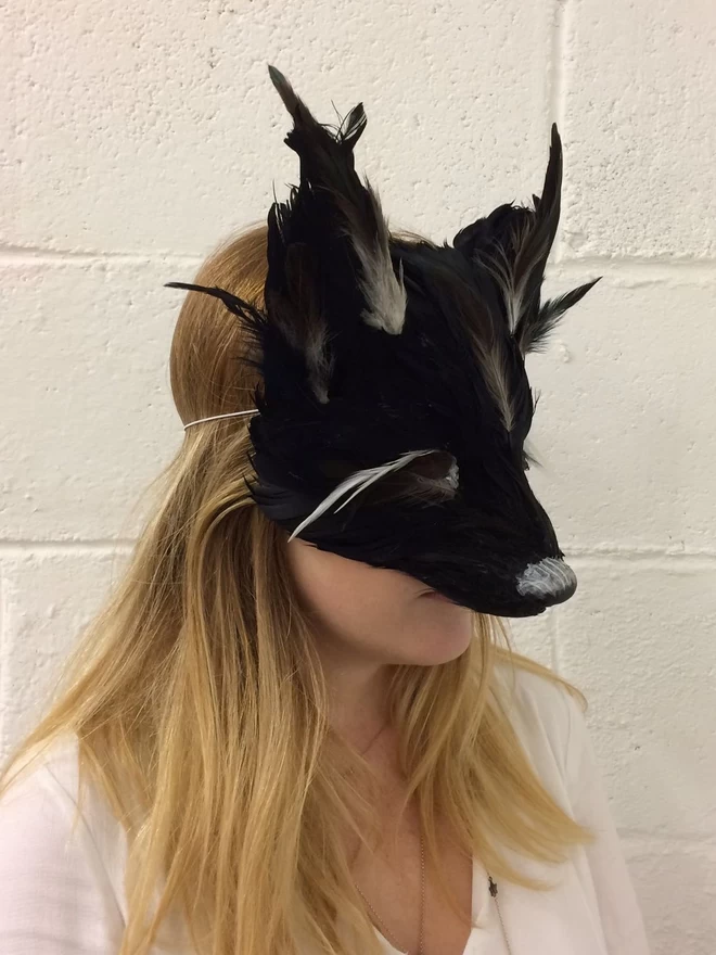 A woman wearing a luxury black fox masquerade mask down over her face