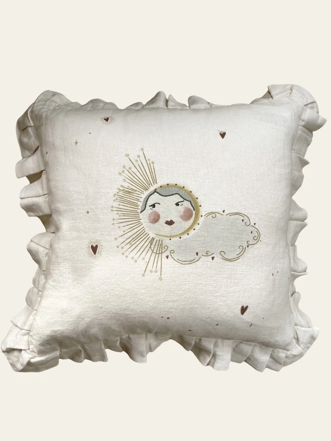 'Love Sun' Linen Ruffled Cushion Cover, a linen cushion with a sun and cloud motif on it sitting on a plain surface.
