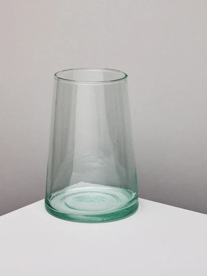 Glass Vase, a large glass vase on a white counter top sitting against a grey backdrop. 