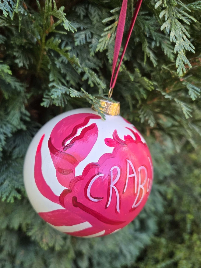 Hand painted christmas baubles hanging in a tree, with crab design. 
