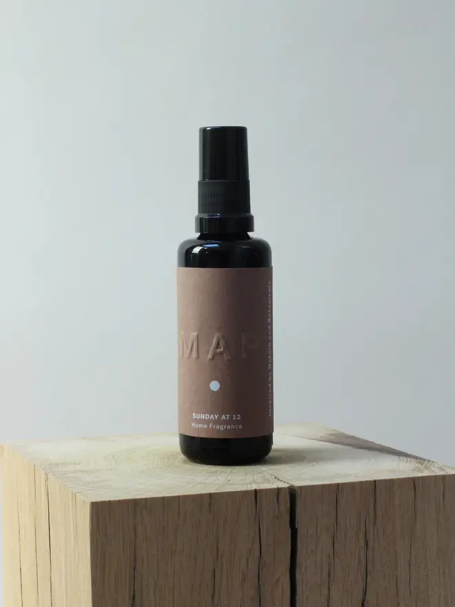 calm aromatherapy candle and home fragrance spray set. spray bottle photographed on wooden surface. 