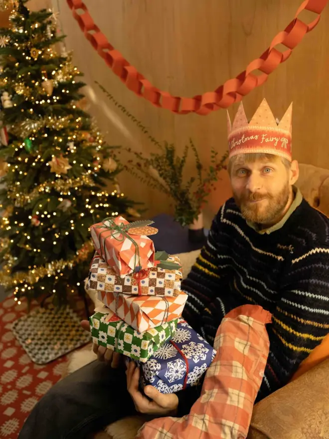 man wearinf pink and red paper crown card with christmas fairy text