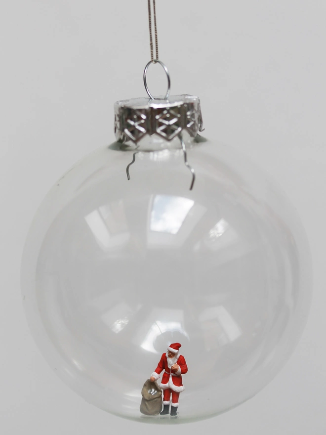 Miniature figure of Santa with a sack of gifts, n a glass Christmas bauble 