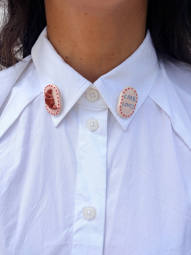 Foodie collar pins. A croissant and a 'carb lover' collar pin worn on the collars of a white shirt