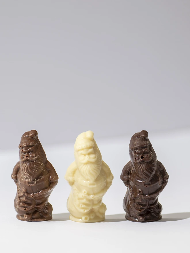 A clear cube filled with Milk, White and Dark chocolate Santa and Reindeer figures, tied with ribbon and a tag