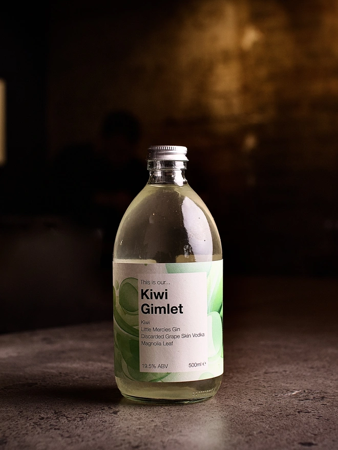 A bottle of Kiwi Gimlet shown against a moody interior background