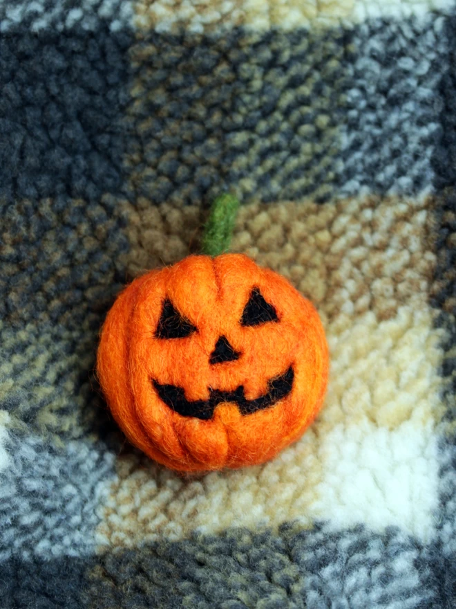 A needle felted pumpkin on a fleecy chequered shirt 